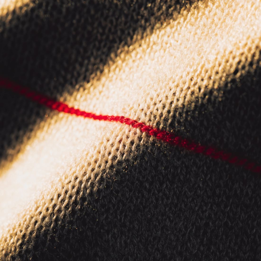 Macro detail of heavyweight cotton weave with a single crimson thread